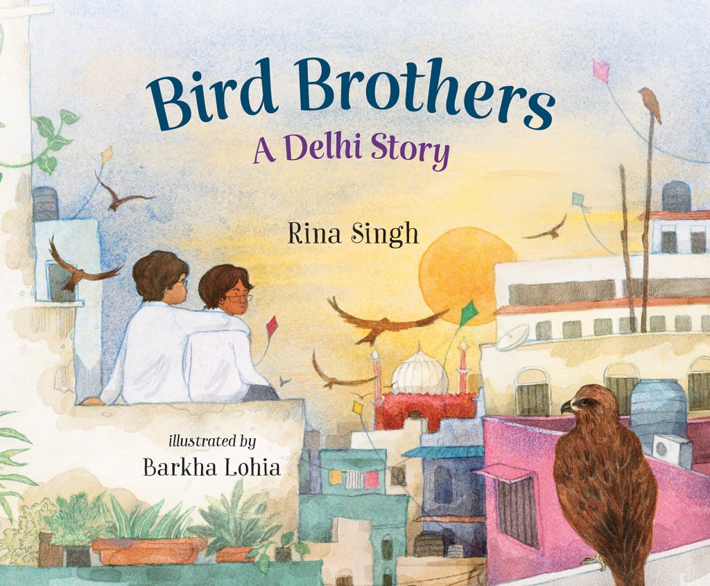 Bird Brothers, A Delhi Story by Rina Singh. Illustrated by Barkha Lohia. Two young people sit on a low wall watching birds swoop among kites as the sun sets over the city of Delhi. One looks back at small brown bird perched on a nearby wall.